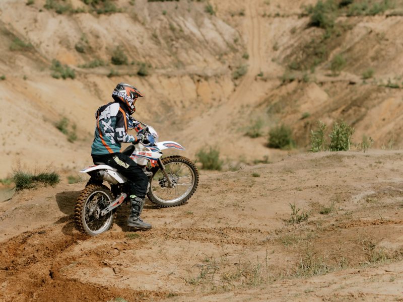 a man riding a motorcycle down a dirt road